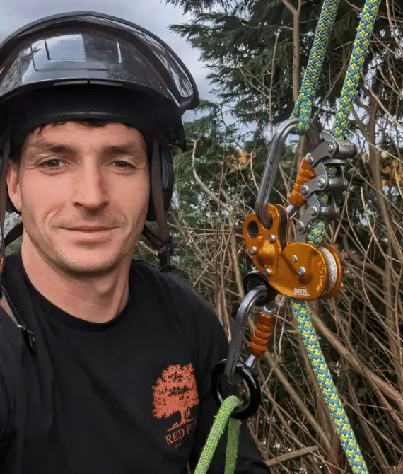 Red Fox Tree Care tree surgeon wearing a safety helmet beside specialist arborist climbing and rigging equipment